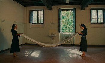 Movie still from “7 Rm., kit., ba...” (1984), directed by Agnès Varda – A woman is holding a large piece of fabric; Wide shot, Low angle