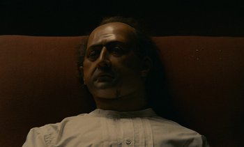 Movie still from “7 Rm., kit., ba...” (1984), directed by Agnès Varda – A person wearing a wig on a couch; Close Up shot, Low angle