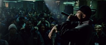 Movie still from “8 Mile” (2002), directed by Curtis Hanson – A crowd of people watching a person sing; Wide shot, Over the shoulder angle