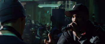 Movie still from “8 Mile” (2002), directed by Curtis Hanson – A man holding a microphone in front of a group of people; Close Up shot, Over the shoulder angle