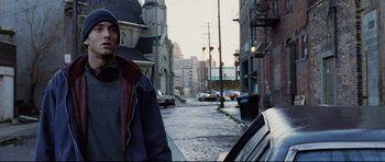 Movie still from “8 Mile” (2002), directed by Curtis Hanson – A man standing next to a car on a street; Medium shot, Low angle