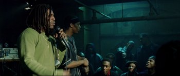 Movie still from “8 Mile” (2002), directed by Curtis Hanson – A group of men standing next to each other on a stage with microphones; Medium shot, Over the shoulder angle