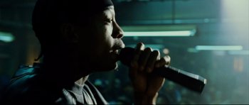 Movie still from “8 Mile” (2002), directed by Curtis Hanson – A man is singing into a microphone in the dark; Close Up shot, Over the shoulder angle