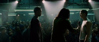 Movie still from “8 Mile” (2002), directed by Curtis Hanson – Two men standing in front of an audience in a dark room; Medium shot, Over the shoulder angle