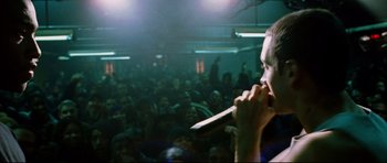 Movie still from “8 Mile” (2002), directed by Curtis Hanson – A man with a microphone in front of a crowd of onlookers; Medium shot, Over the shoulder angle