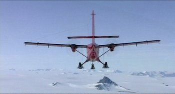 Movie still from “9 Songs” (2004), directed by Michael Winterbottom – A red airplane flying over a snow covered mountain; Extreme Wide shot, High angle
