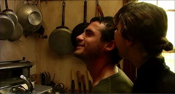 Movie still from “9 Songs” (2004), directed by Michael Winterbottom – A man standing next to another man in a kitchen; Close Up shot, Over the shoulder angle