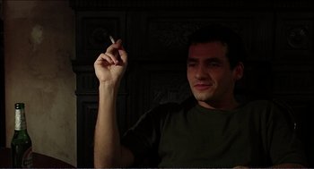 Movie still from “9 Songs” (2004), directed by Michael Winterbottom – A man holding a cigarette in his right hand; Close Up shot, Low angle