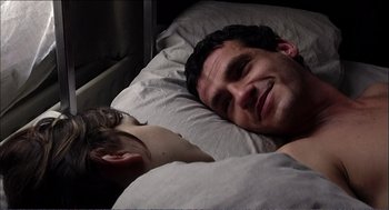 Movie still from “9 Songs” (2004), directed by Michael Winterbottom – A man laying in bed next to a sleeping woman; Close Up shot, High angle