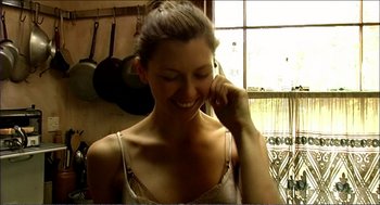 Movie still from “9 Songs” (2004), directed by Michael Winterbottom – A woman smiling while talking on a cell phone; Close Up shot, Low angle