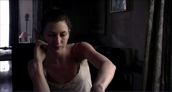 Movie still from “9 Songs” (2004), directed by Michael Winterbottom – A woman sitting down talking on a phone; Close Up shot, Low angle