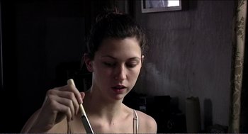 Movie still from “9 Songs” (2004), directed by Michael Winterbottom – A woman is holding a knife in her hand; Close Up shot, Low angle