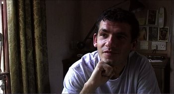 Movie still from “9 Songs” (2004), directed by Michael Winterbottom – A person with his hand on his chin; Close Up shot, High angle