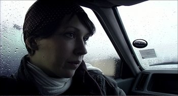 Movie still from “9 Songs” (2004), directed by Michael Winterbottom – A woman sitting in the passenger seat of a car looking out the window; Close Up shot, Low angle