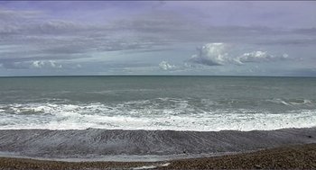 Movie still from “9 Songs” (2004), directed by Michael Winterbottom – A view of the ocean from the beach; Extreme Wide shot, High angle