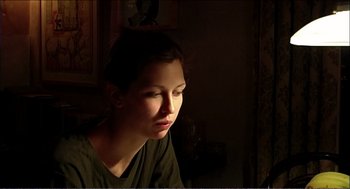 Movie still from “9 Songs” (2004), directed by Michael Winterbottom – A woman sitting in a room with her head turned to the side; Close Up shot, Low angle