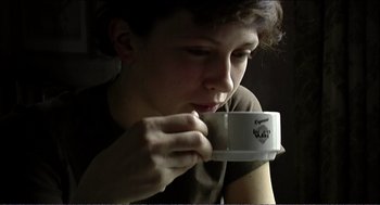 Movie still from “9 Songs” (2004), directed by Michael Winterbottom – A woman is drinking a cup of coffee; Close Up shot, Over the shoulder angle