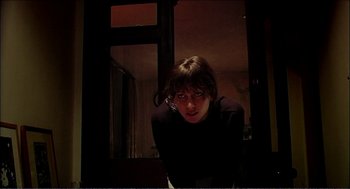 Movie still from “9 Songs” (2004), directed by Michael Winterbottom – A woman in a black shirt is standing in front of a window; Close Up shot, Low angle