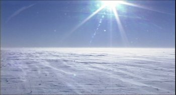 Movie still from “9 Songs” (2004), directed by Michael Winterbottom – The sun is shining over a snow covered field; Extreme Wide shot, High angle