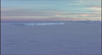 Movie still from “9 Songs” (2004), directed by Michael Winterbottom – A view of the ocean from the beach at sunset; Extreme Wide shot, High angle