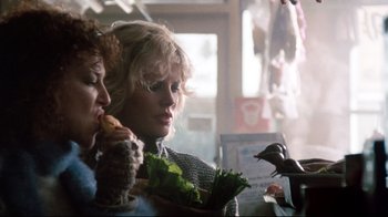Movie still from “9½ Weeks” (1986), directed by Adrian Lyne – Two women are sitting at a table with a bowl of lettuce; Medium shot, Over the shoulder angle