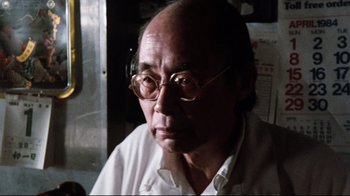 Movie still from “9½ Weeks” (1986), directed by Adrian Lyne – An older man wearing glasses and a white shirt; Close Up shot, Low angle