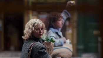 Movie still from “9½ Weeks” (1986), directed by Adrian Lyne – A woman holding a paper bag with a plant in it; Medium shot, Over the shoulder angle