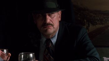 Movie still from “9½ Weeks” (1986), directed by Adrian Lyne – A man in a suit and tie holding a glass of wine; Close Up shot, Low angle