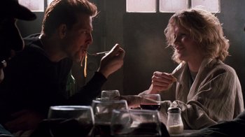 Movie still from “9½ Weeks” (1986), directed by Adrian Lyne – A man and a woman sitting at a dinner table; Medium shot, Low angle