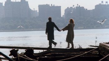 Movie still from “9½ Weeks” (1986), directed by Adrian Lyne – A man and a woman holding hands while standing next to a body of water; Wide shot, Low angle