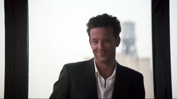 Movie still from “9½ Weeks” (1986), directed by Adrian Lyne – A person wearing a suit and smiling; Close Up shot, Low angle