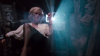 Movie still from “9½ Weeks” (1986), directed by Adrian Lyne – A woman sitting on a chair in a dark room; Medium shot, Low angle