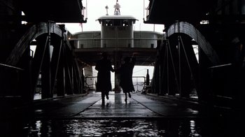Movie still from “9½ Weeks” (1986), directed by Adrian Lyne – Two people walking towards a boat in the water; Extreme Wide shot, Low angle