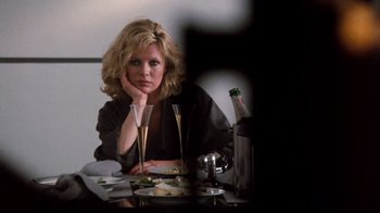 Movie still from “9½ Weeks” (1986), directed by Adrian Lyne – A woman sitting at a table with a plate of food; Close Up shot, Over the shoulder angle