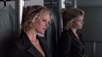 Movie still from “9½ Weeks” (1986), directed by Adrian Lyne – A woman in a black suit looking at herself in a mirror; Close Up shot, Low angle