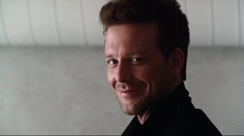 Movie still from “9½ Weeks” (1986), directed by Adrian Lyne – A person wearing a black shirt smiling; Close Up shot, Low angle