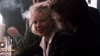 Movie still from “9½ Weeks” (1986), directed by Adrian Lyne – A woman sitting next to a man in a suit; Close Up shot, Low angle