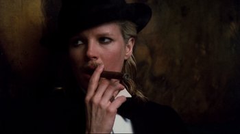 Movie still from “9½ Weeks” (1986), directed by Adrian Lyne – A woman wearing a hat and smoking a cigar; Close Up shot, Low angle