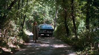 Movie still from “9½ Weeks” (1986), directed by Adrian Lyne – A woman walking down a dirt road with a car in the background; Extreme Wide shot, High angle