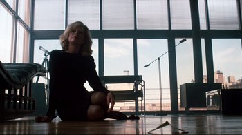 Movie still from “9½ Weeks” (1986), directed by Adrian Lyne – A woman sitting on the ground in a room; Wide shot, Low angle