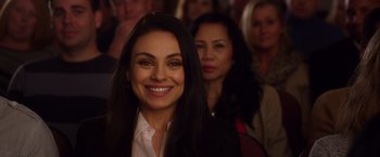 Movie still from “A Bad Moms Christmas” (2017), directed by Scott Moore – A woman smiles brightly at the camera in front of a group of people; Close Up shot, Over the shoulder angle