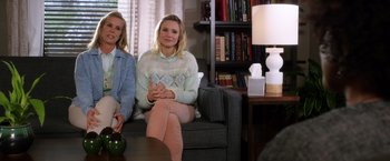 Two women sitting on a couch in front of a lamp