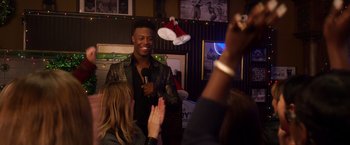 Movie still from “A Bad Moms Christmas” (2017), directed by Scott Moore – A man standing in front of a crowd of onlookers holding microphones; Medium shot, Over the shoulder angle