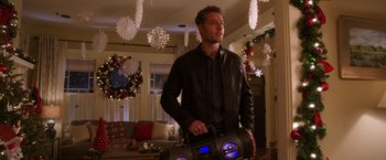Movie still from “A Bad Moms Christmas” (2017), directed by Scott Moore – A man holding a boombox while standing in a living room; Medium shot, Over the shoulder angle