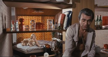 Movie still from “A Bay of Blood” (1971), directed by Mario Bava – A man and a woman are sitting on a bunk bed; Medium shot, Low angle