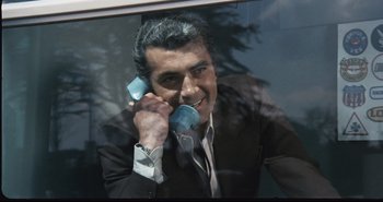 Movie still from “A Bay of Blood” (1971), directed by Mario Bava – A man talking on a phone while looking out a window; Close Up shot, High angle