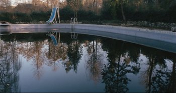 Movie still from “A Bay of Blood” (1971), directed by Mario Bava – A swimming pool with a slide in the middle of the pool; Extreme Wide shot, High angle
