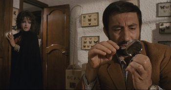 Movie still from “A Bay of Blood” (1971), directed by Mario Bava – A man looking at a butterfly through a magnifying glass; Medium shot, Low angle