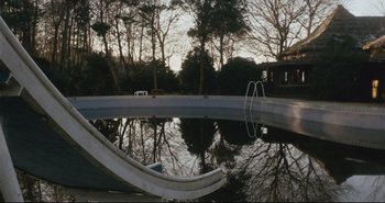 Movie still from “A Bay of Blood” (1971), directed by Mario Bava – A pool that has a slide in the middle of it; Extreme Wide shot, High angle