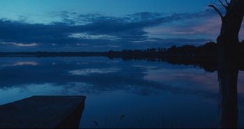 Movie still from “A Bay of Blood” (1971), directed by Mario Bava – A body of water at night with a boat in the foreground; Extreme Wide shot, Low angle